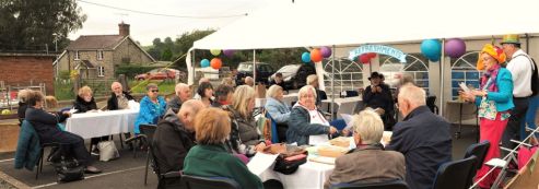 Photo of an event showing people sat round tables outdoors